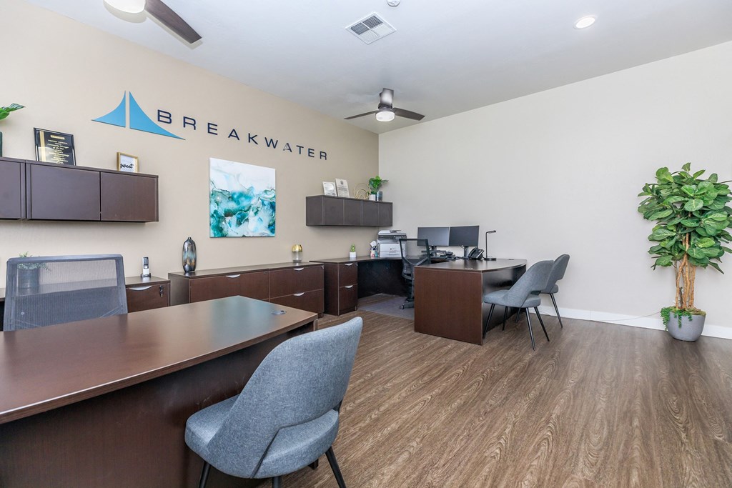 an office with desks and chairs and a breakwater sign on the wall