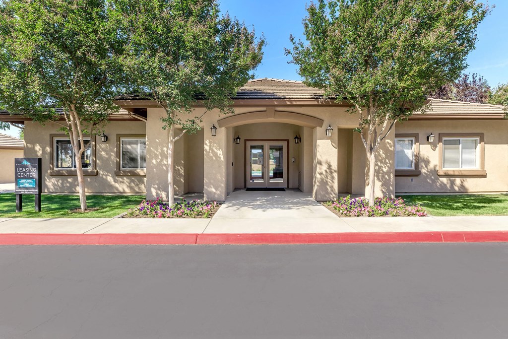 the front entrance to a tan house with trees and a sidewalk