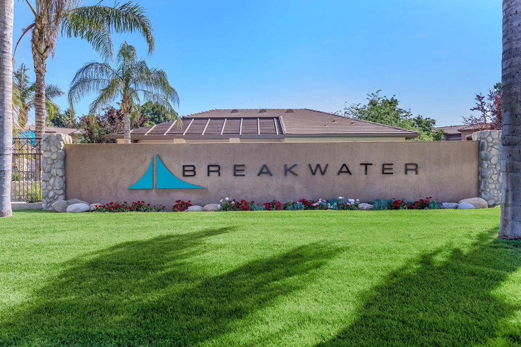 the front of the breakwater building with palm trees and grass