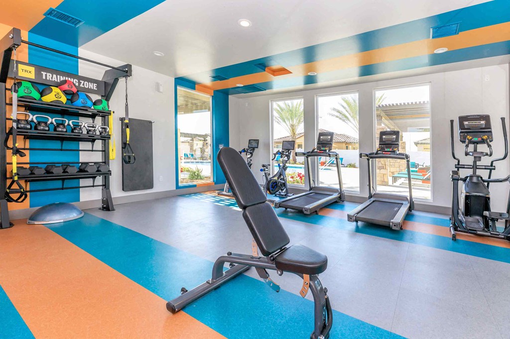 a gym with weights and cardio equipment on the floor and windows