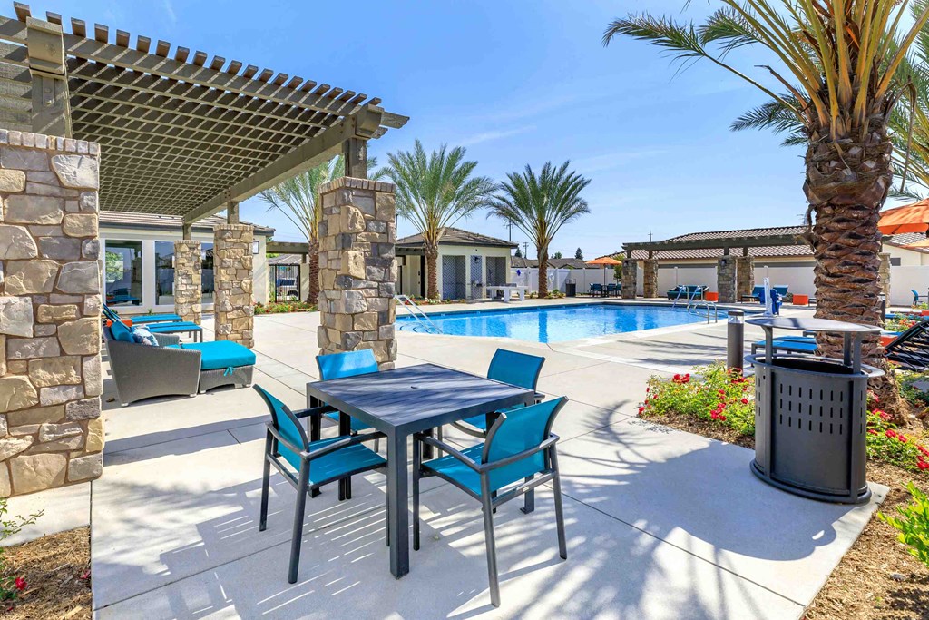 a patio with a table and chairs next to a swimming pool