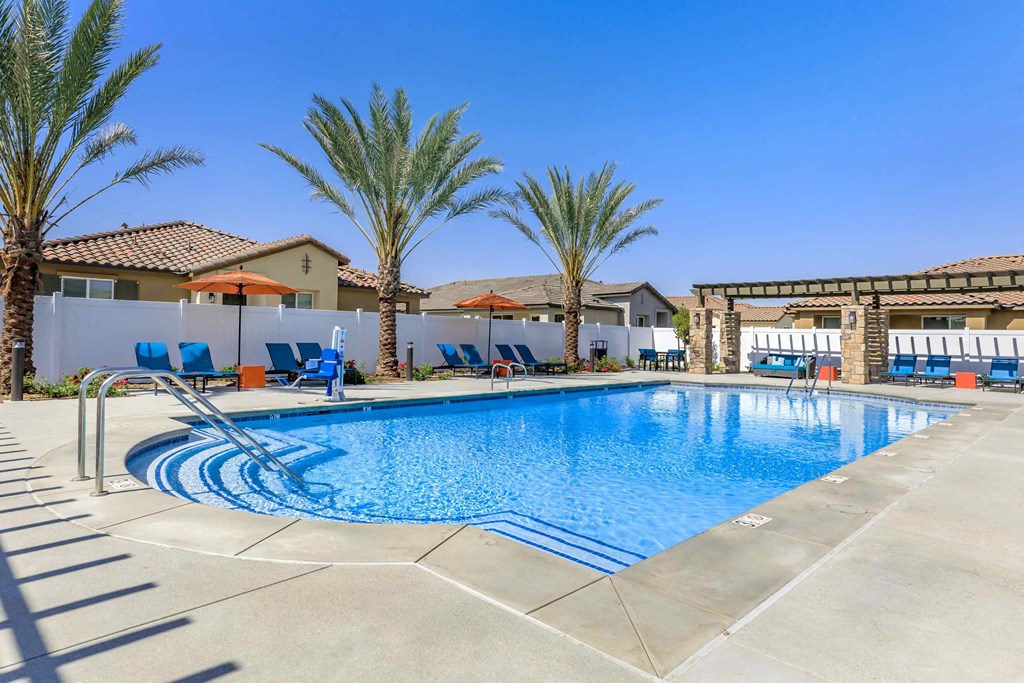 a swimming pool with chairs and palm trees
