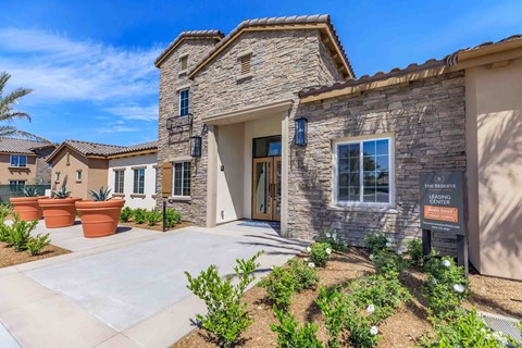 a home with a stone facade and a sidewalk in front of it