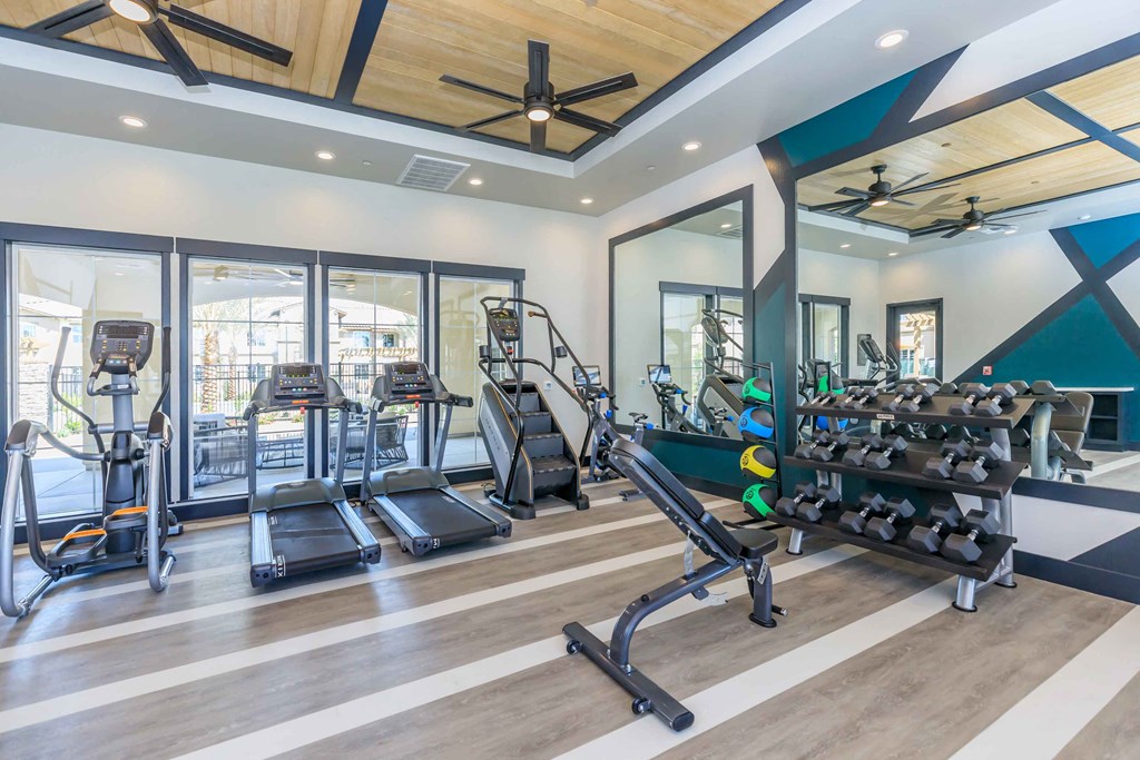 a gym with weights and cardio equipment and glass doors