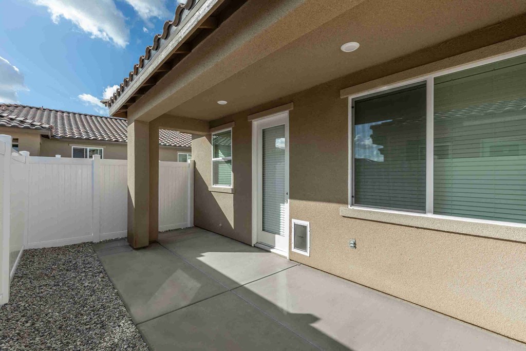 a patio in front of a house with a white fence
