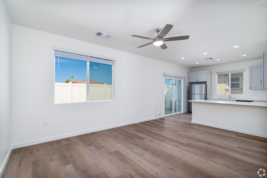 a living room and kitchen with white walls and a ceiling fan