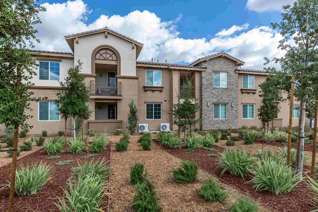 an exterior view of an apartment building with a garden