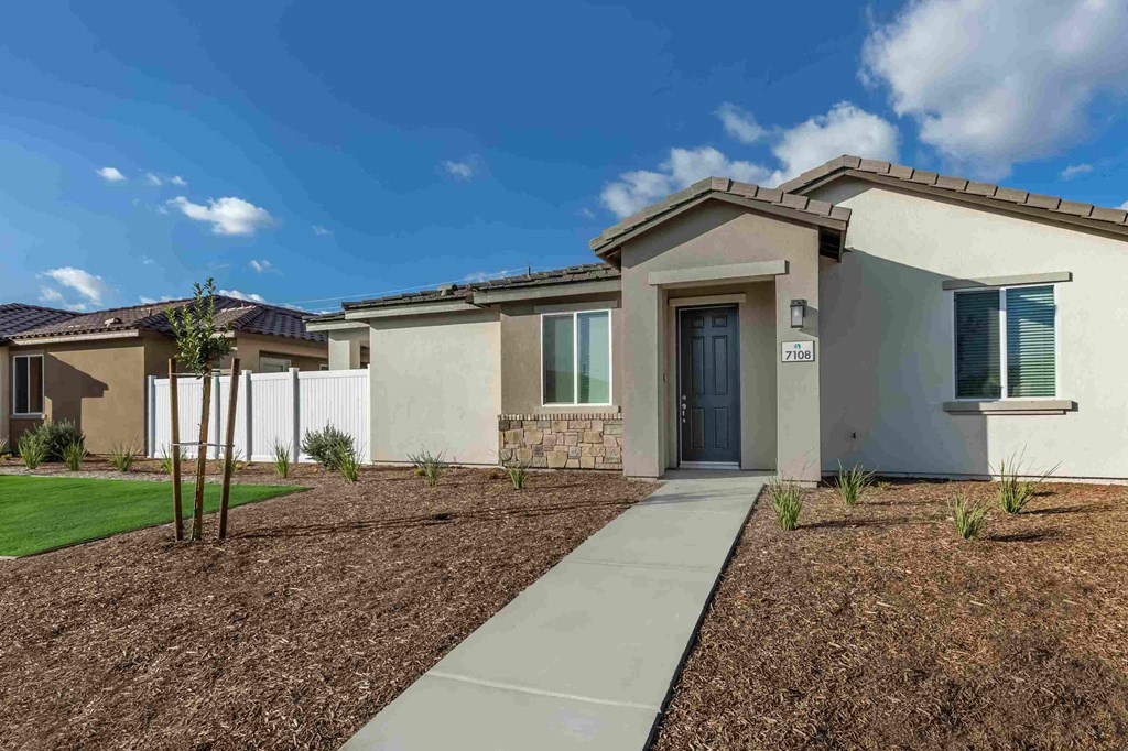 a home is shown with a sidewalk and grass