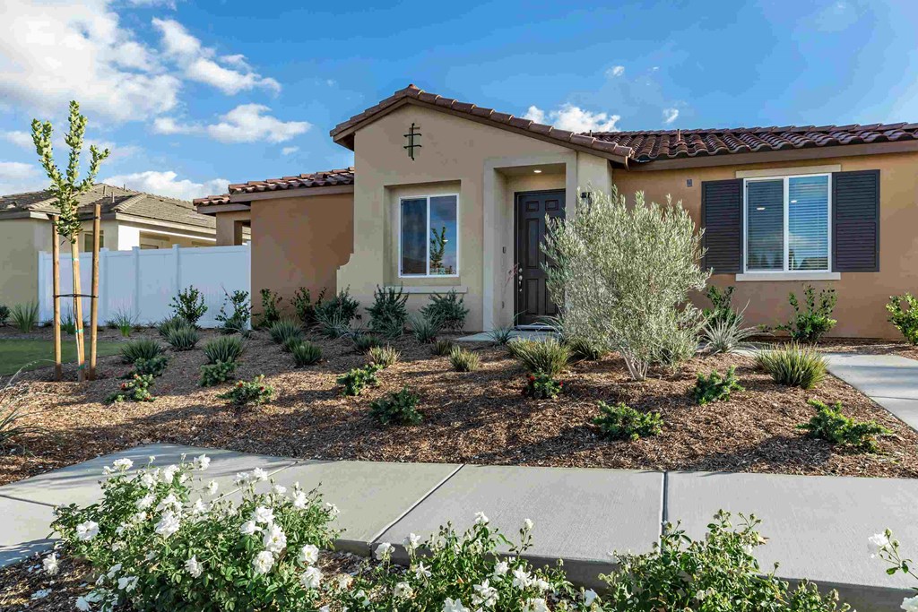 a house with a front yard with plants and a sidewalk