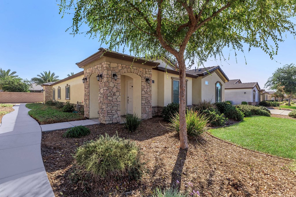 a house with a tree and a sidewalk in front of it