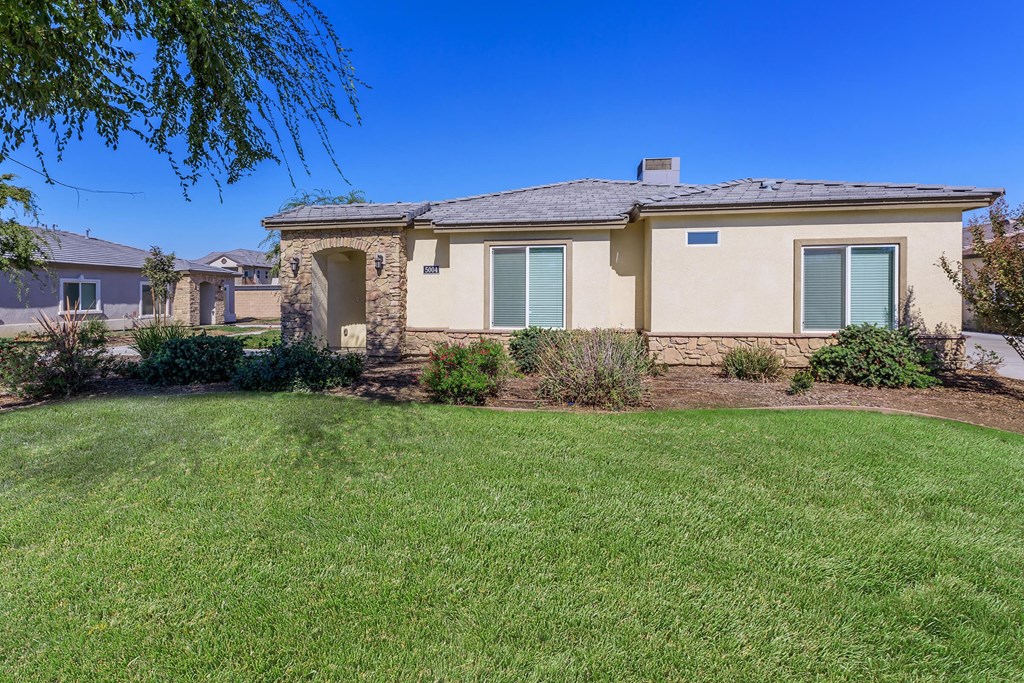 a beige house with green shutters and a lawn