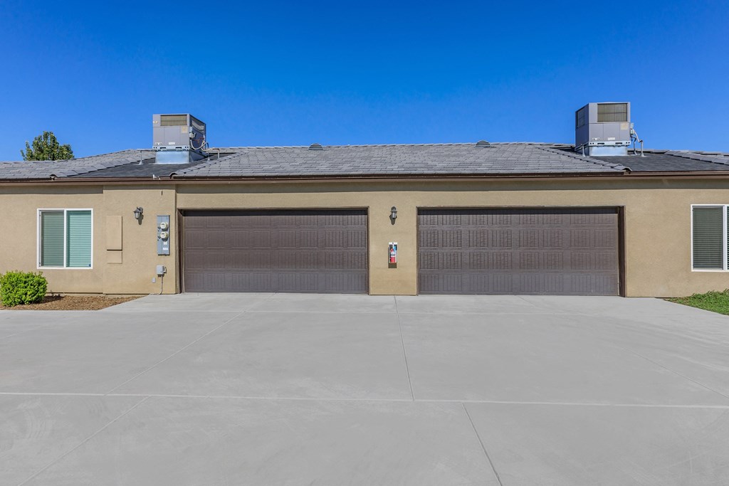 a beige house with two garage doors and a driveway