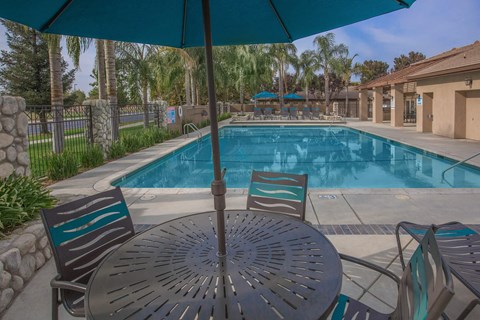 a swimming pool with a table and chairs under an umbrella
