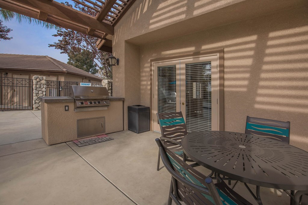 a patio with a grill and a table with chairs