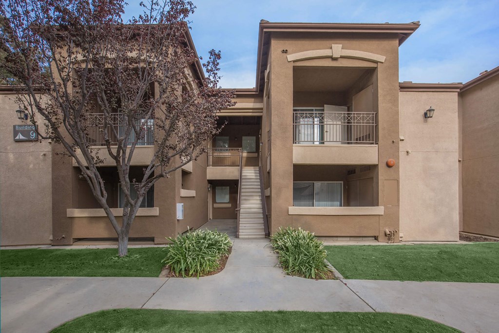 an apartment building with a staircase and a tree in front of it