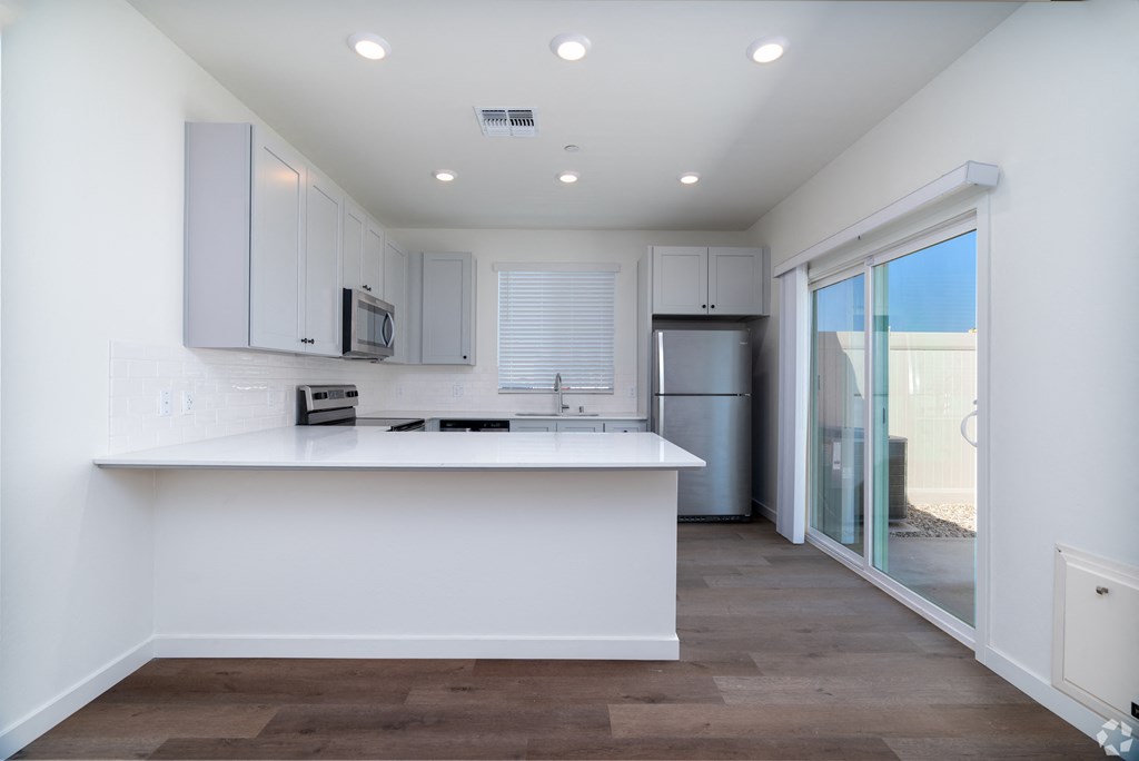 a white kitchen with a large breakfast bar and a sliding glass door