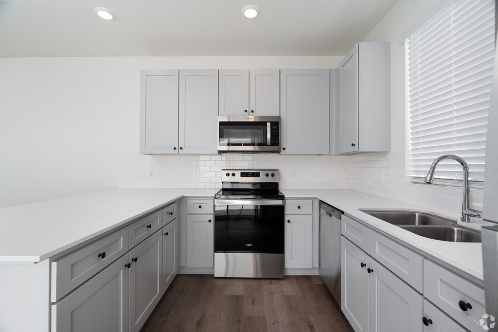 a kitchen with gray cabinets and a sink and a stove