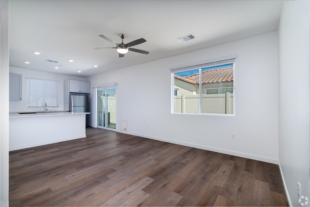 a living room and kitchen with a ceiling fan and a window