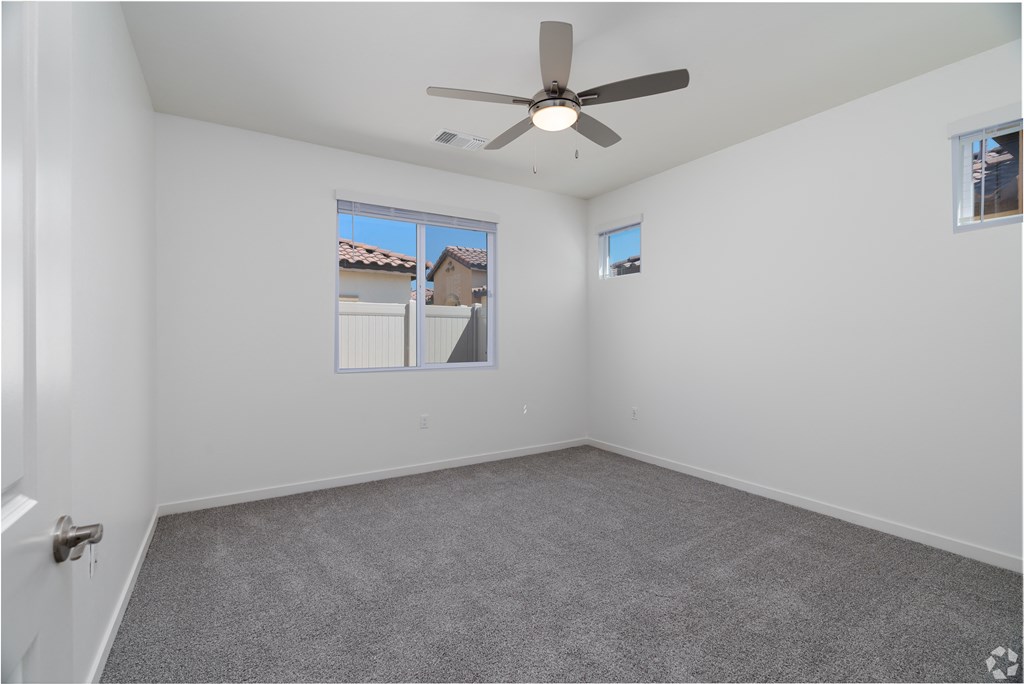 an empty bedroom with a ceiling fan and a window