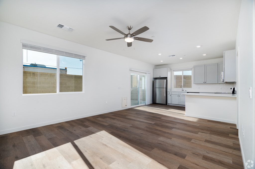 a living room with a ceiling fan and a kitchen