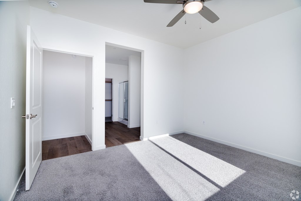 a bedroom with white walls and a ceiling fan