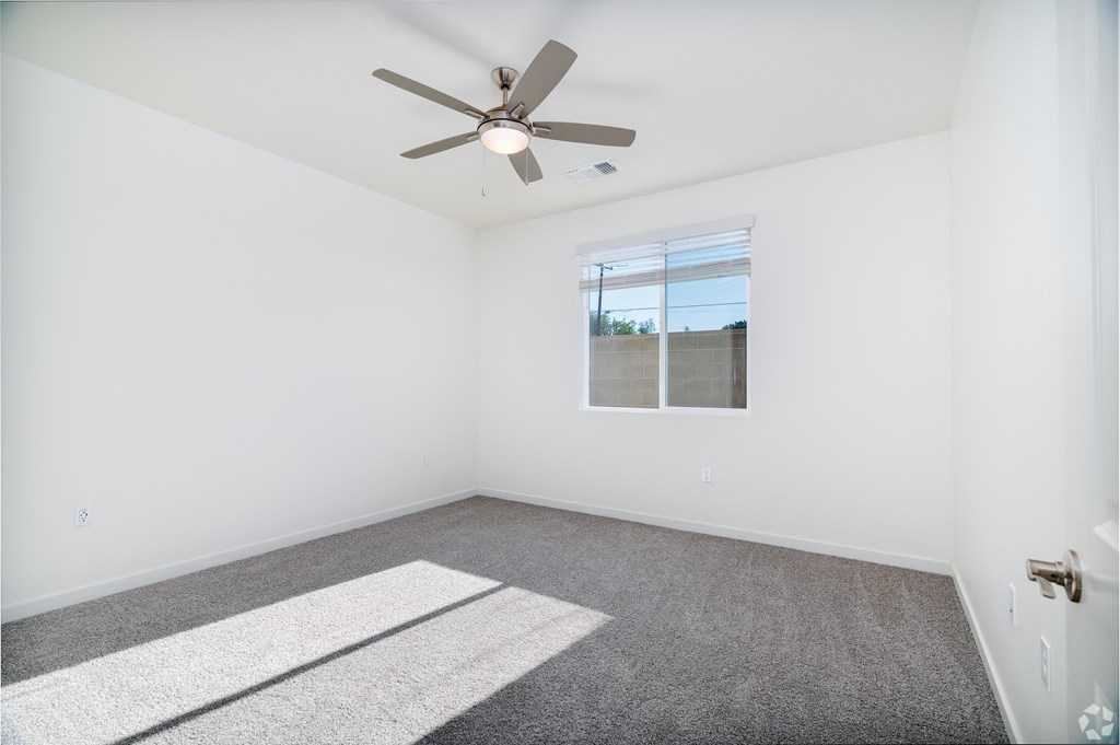 an empty bedroom with a ceiling fan and a window