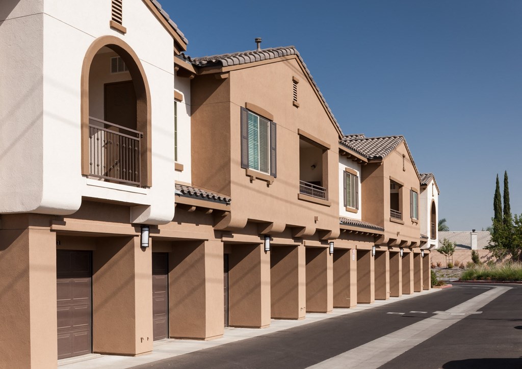 a row of beige buildings with garage doors and balconies