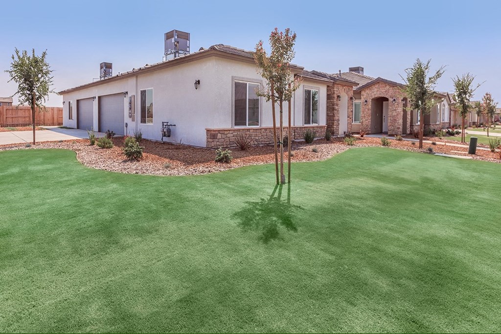 a backyard with a house and a yard with green grass