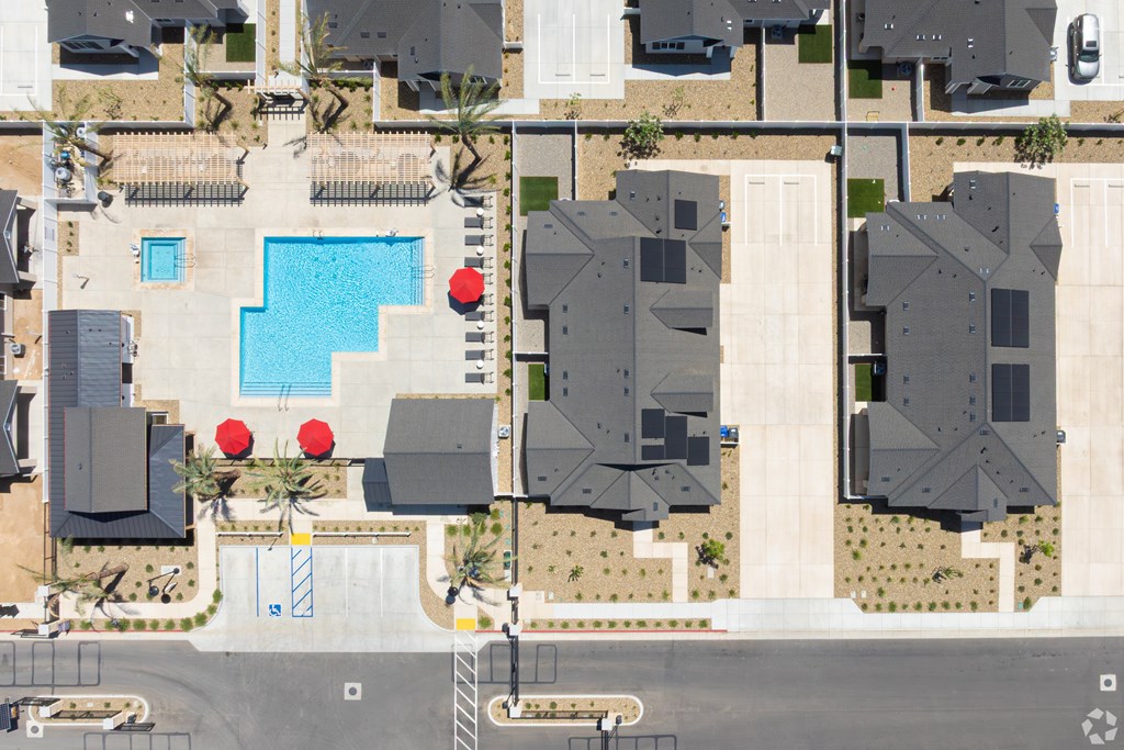 A bird's eye view of a residential area with houses, a pool, and a parking lot.