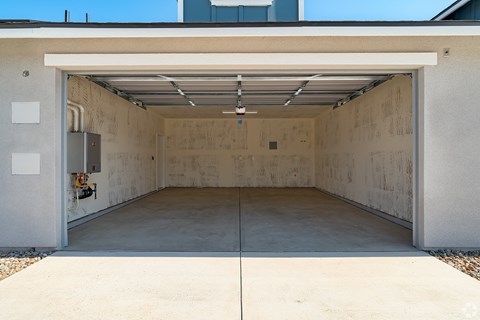 a garage with a concrete floor and a steel door open