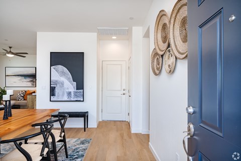 a dining room with a wooden table and chairs and a hallway with a blue door