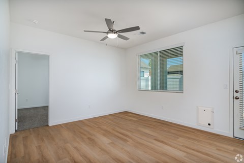 a living room with white walls and wood flooring and a ceiling fan