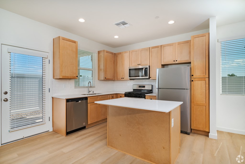 a kitchen with wooden cabinets and stainless steel appliances and a white counter top