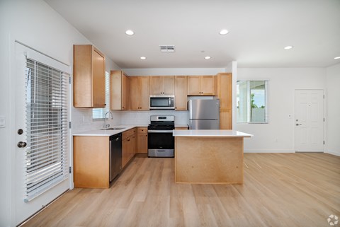 a kitchen with wooden cabinets and a large island with a stove and a refrigerator