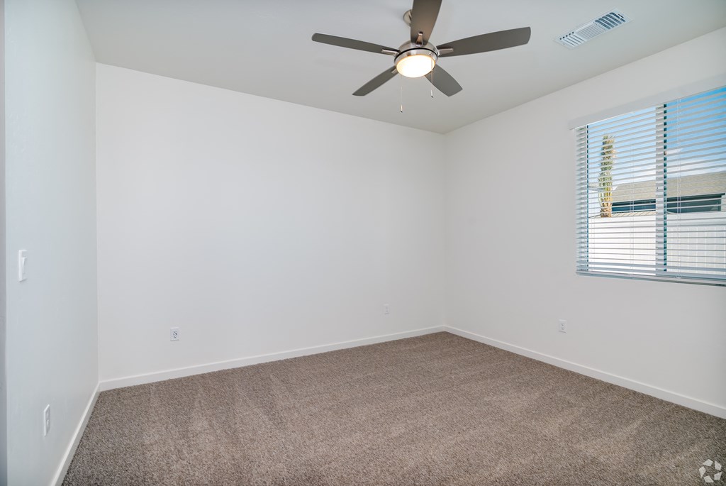an empty room with a ceiling fan and a window