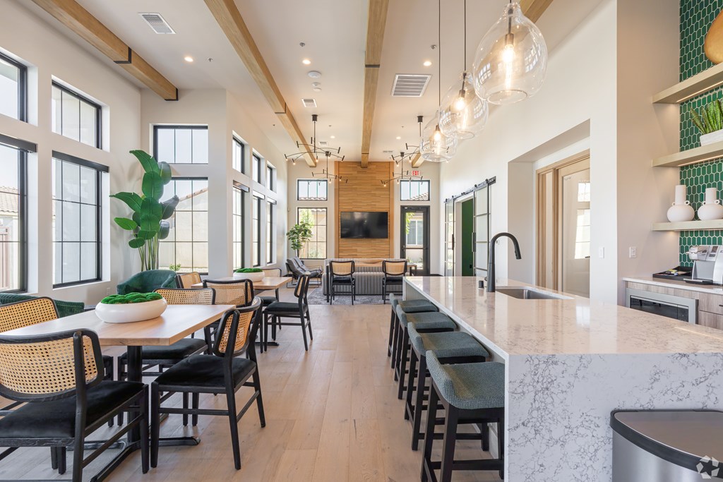 A modern kitchen with a long bar and a dining table with chairs.