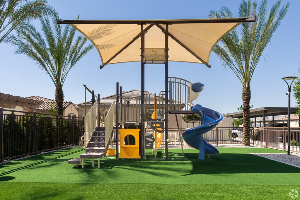 A playground with a yellow slide and a canopy.
