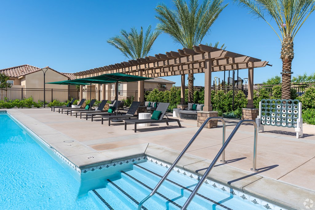 A pool with a slide and a shaded area with chairs.