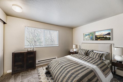 A bedroom with a large bed and a window with blinds.