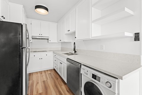 A black refrigerator is in a white kitchen.
