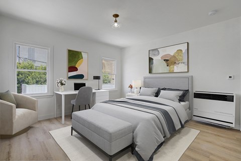 a bedroom with a bed and a desk and two windows