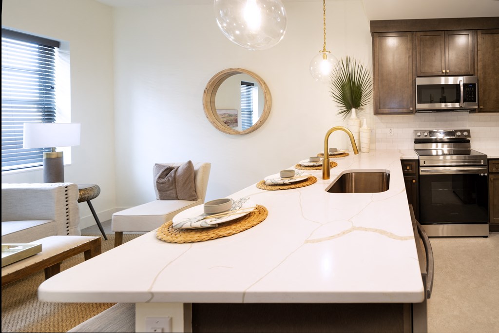 a kitchen and living room with a white counter top and a sink