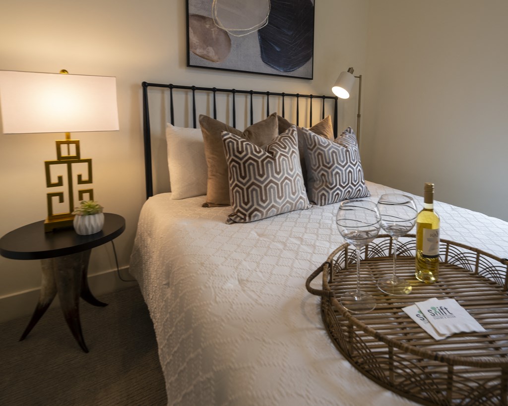 a bedroom with a bed and a bottle of wine on it