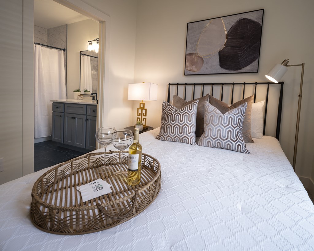 a bedroom with a bed and a bottle of wine on it