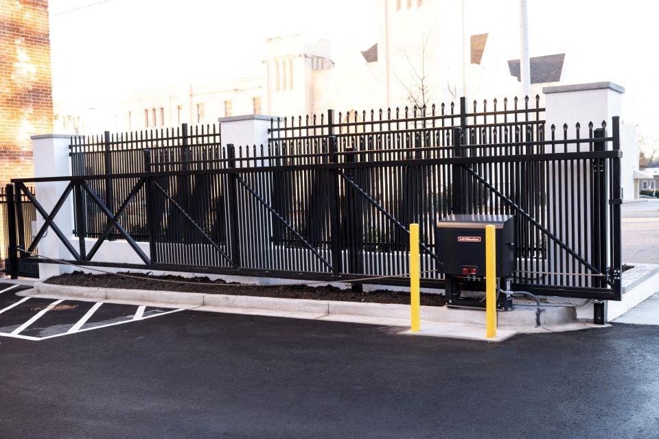 a gate with a mail box in front of a parking lot