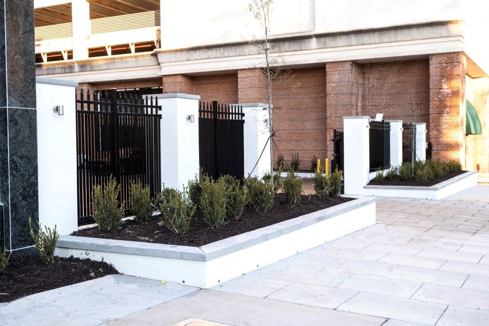 a courtyard with a fence and plants in front of a building