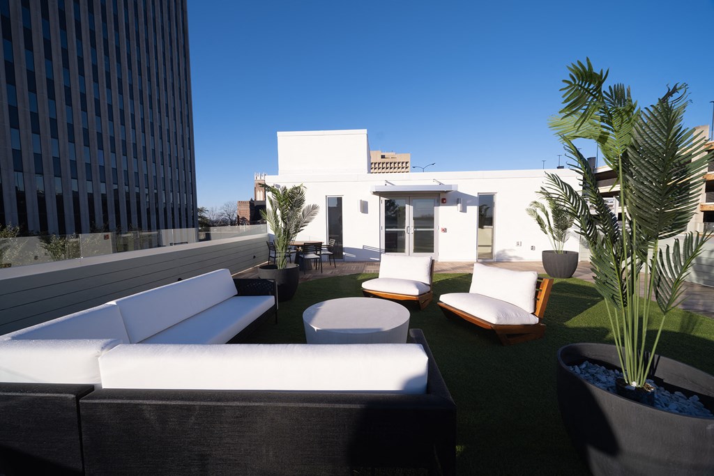 a roof terrace with couches and chairs and potted plants