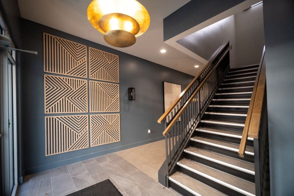 a staircase in a house with blue walls and a geometric wall art