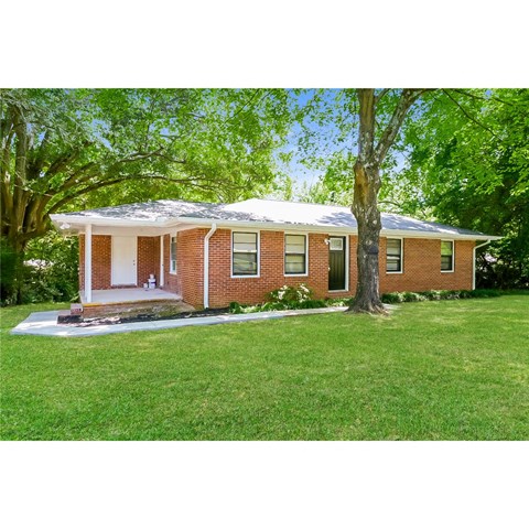 a small brick house with a tree in front of it