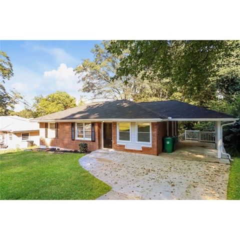 a small brick house with a yard and a driveway